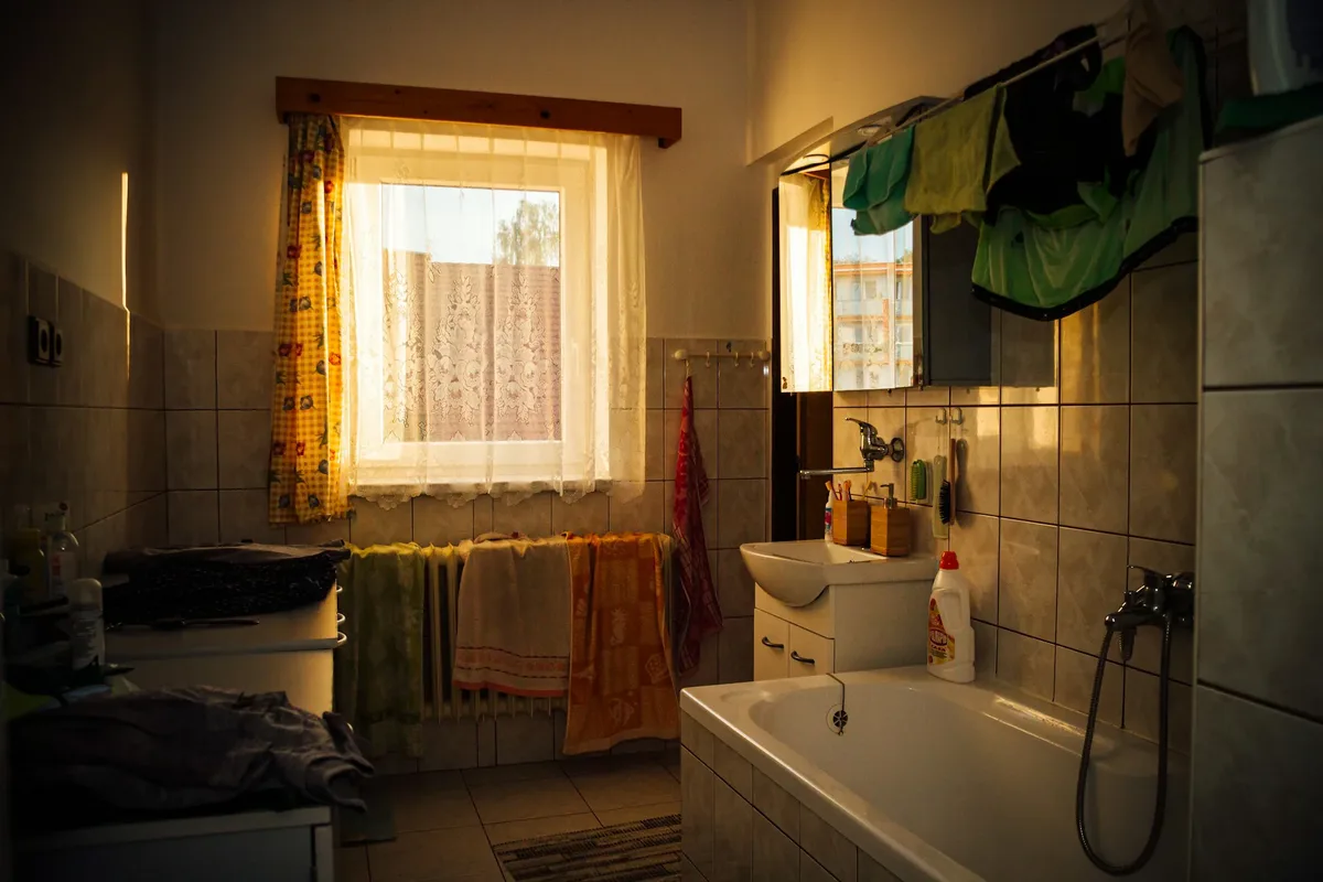 Gedateerde badkamer met ligbad, wastafel en handdoeken over de radiator onder het raam