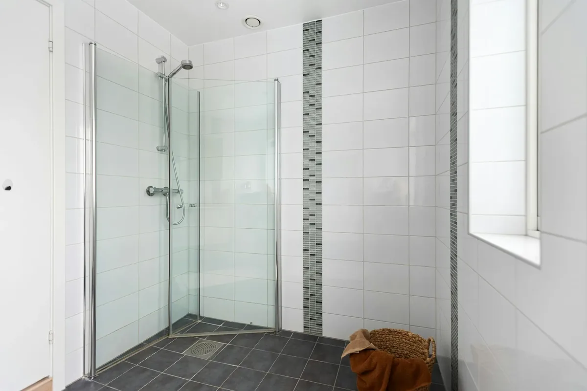 Betegelde badkamer met glazen douchewand en een rond afvoerputje in de vloer